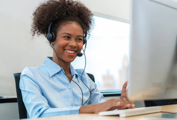 istock Africa American friendly operator woman agent with headsets and computer working in a call centermodern office. Young female conference with customer and smile. Customer support and happywork 1426548911