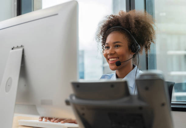 istock Africa American friendly operator woman agent with headsets and computer working in a call center
modern office. Young female conference with customer and smile. Customer support and happy
work 1426548931