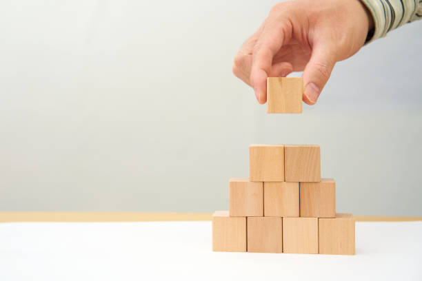 istock businessman hand put wood block on top stack for profress success 1426549421