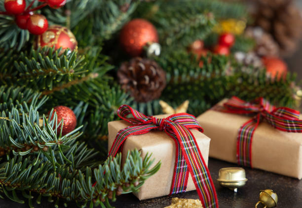 istock Wrapped gift boxes between Christmas decorations, pine cones and green fir branches 1426554991