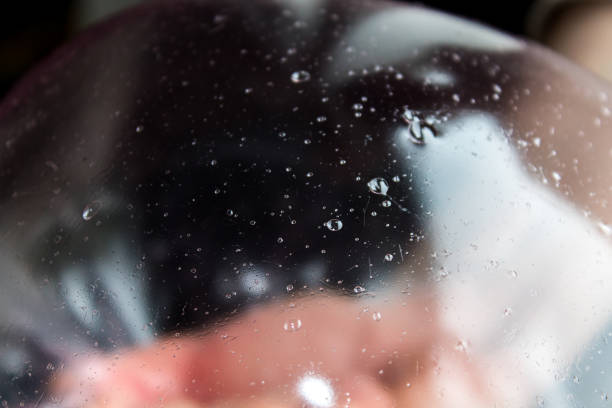 Abstract image obtained from slime modeling, with a large and transparent bubble and other smaller bubbles of air, on a colored and blurred background.
