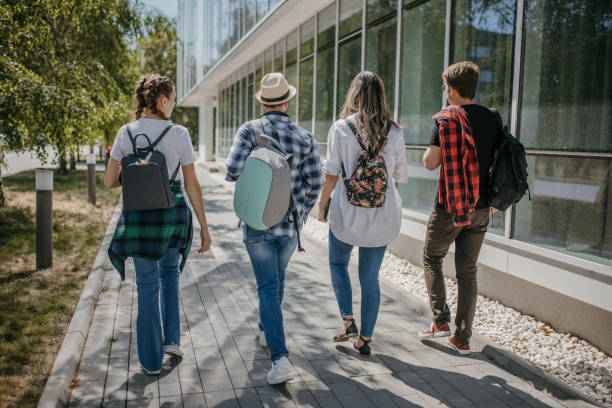 istock Happy young friends walking near university building after studies 1426555887