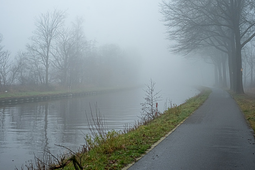 Belgian countryside canal with fog and reflection at sunrise in wintertime. High quality photo
