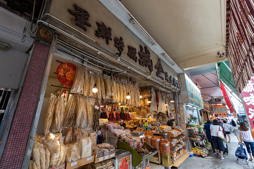 Hong Kong - September 23, 2022 : People walk past the Kam Shing Dried Seafood Store in Kowloon City, Kowloon, Hong Kong. The shop has opened in Kowloon City for more than 60 years.