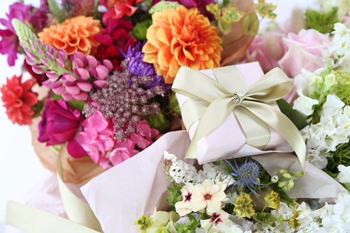 Womens hand holding blank paper card over beautiful bouquet of colorful flowers. Love, Birthday, Valentines day concept