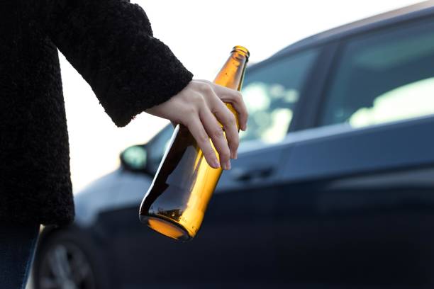 Young woman drinking while driving. Young adult drinking beer while driving, she is going to a party. driving under the influence stock pictures, royalty-free photos & images