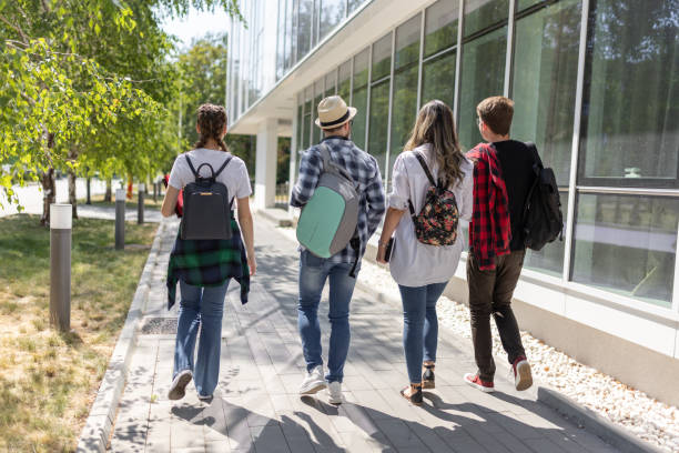 istock Happy young friends walking near university building after studies 1426558842