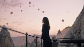 休暇中に滞在するホテルの屋上で空を飛ぶ熱気球を見るのを楽しむ女性観光客