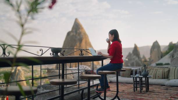 Young female freelancer tourist using her laptop at rooftop patio of hotel stock photo