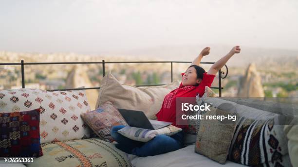 Young Female Freelancer Tourist Using Her Laptop At Rooftop Patio Of Hotel Stock Photo - Download Image Now