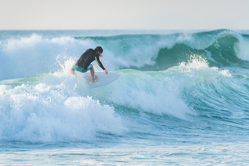 Local surfer riding waves with a short board in Furadouro beach, Portugal. Men catching waves in ocean. Surfing action water board sport.