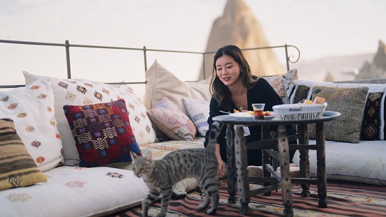 A female tourist is enjoying having breakfast on the rooftop of the hotel where she is staying during her travel.