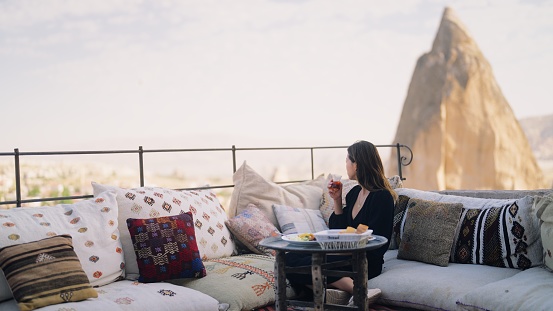 A female tourist is enjoying having breakfast on the rooftop of the hotel where she is staying during her travel.