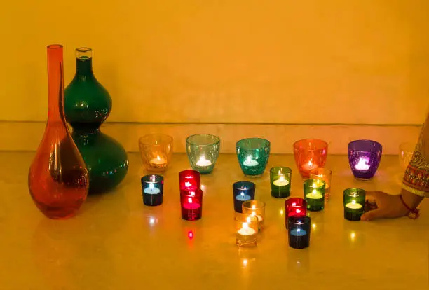 Photo of Closeup view of Christmas or Diwali decorations with glowing tea light candles in glass candle holders or diya.