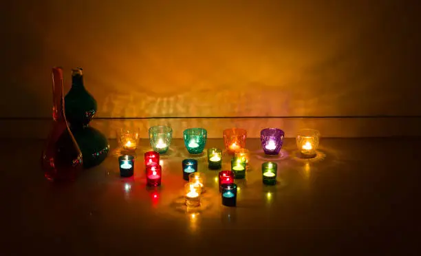 Photo of Diwali celebrations done with decorating glass candle holders with glowing candle tea lights.Light  reflections on the background.