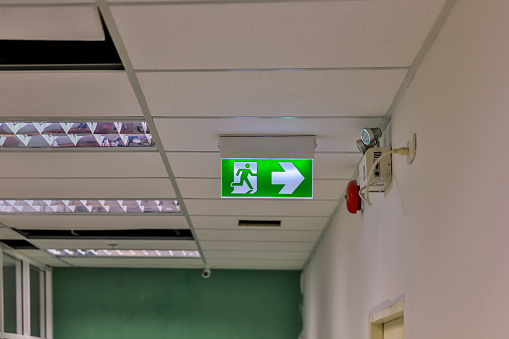 Green emergency exit sign on ceiling inside of building
