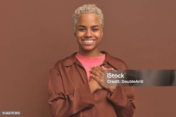 Young Goodnatured African American Woman Puts Palms On Heart Shows Gratitude Stock Photo - Download Image Now