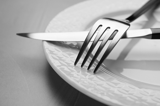 Plate with fork and knife on grey table, closeup