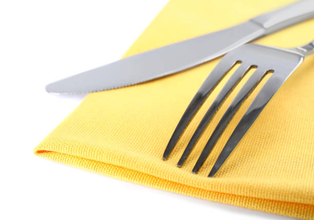 Yellow napkin with fork and knife on white background, closeup