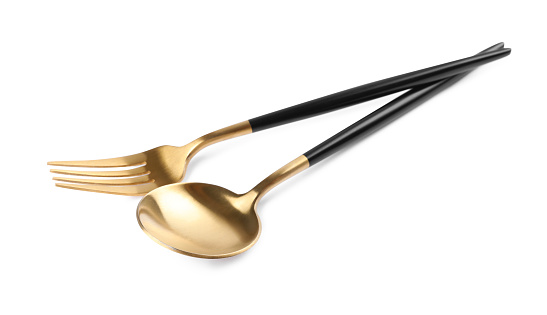 New golden fork and spoon with black handles on white background