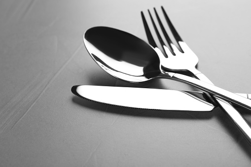 New shiny cutlery on grey table, closeup