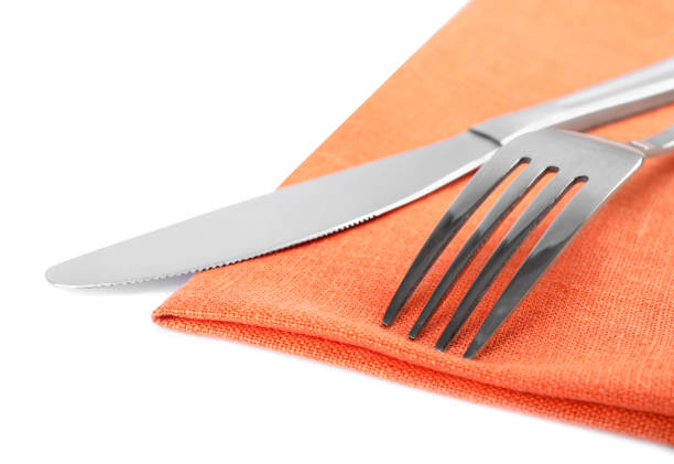 istock Orange napkin with fork and knife on white background, closeup 1426576026