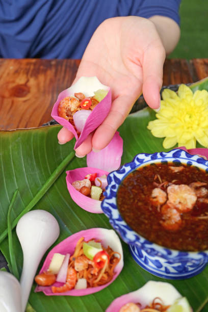 istock Woman's Hand Holding Fresh Lotus Petal Wrapped Appetizer before Putting Spicy Dip 1426586256