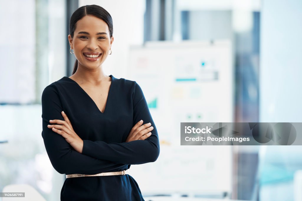 Confident, happy and smiling business woman standing with her arms crossed while in an office with a positive mindset and good leadership. Portrait of an entrepreneur feeling motivated and proud Businesswoman Stock Photo