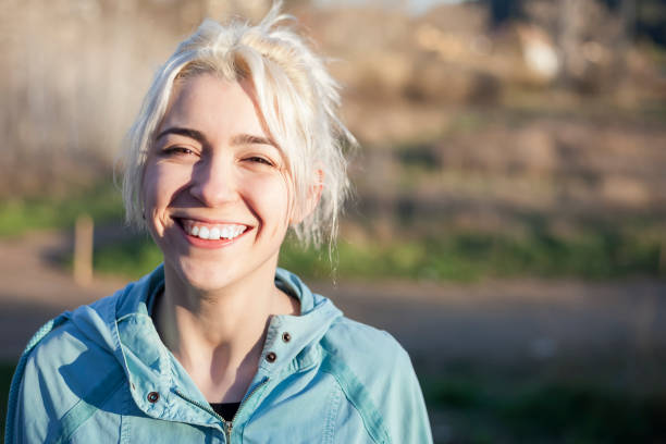 Fit smiling blonde looking at camera in a park on a sunny day