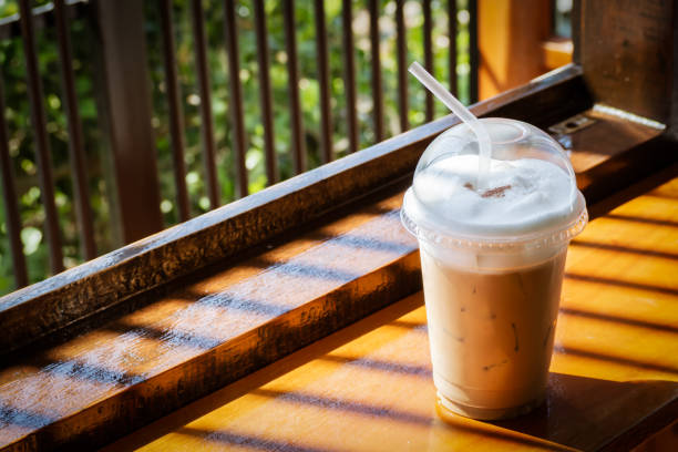istock ice cappuccino in plastic cup on wooden table. Shadow and contrast  with copy space in warm color tone. 1426588049