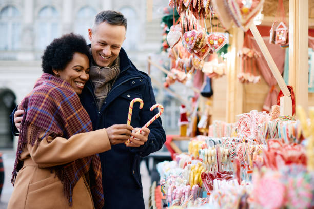 Happy couple making heart shape with Christmas candy canes.