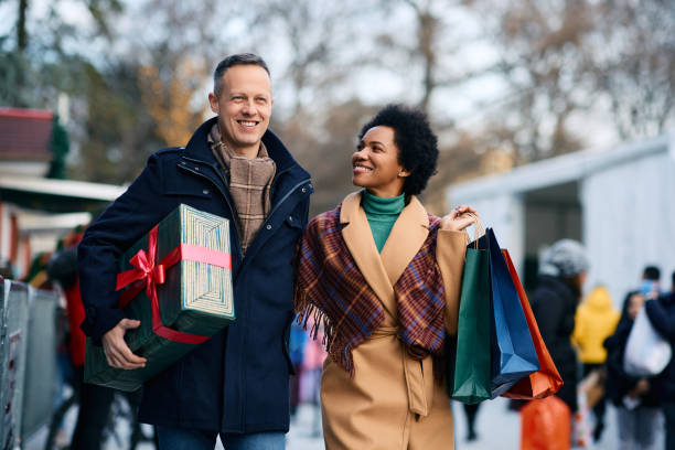 feliz pareja multirracial disfrutando en las compras navideñas. - merchandise fotografías e imágenes de stock