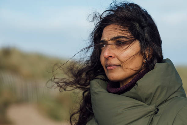 Closeup of young woman face covered with flying hair in windy day at mountain