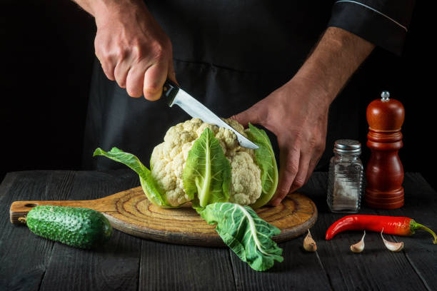 o chef está cortando couve-flor em uma cozinha de restaurante. a ideia de uma deliciosa dieta para o café da manhã ou jantar. - hotel commercial kitchen organic salad - fotografias e filmes do acervo