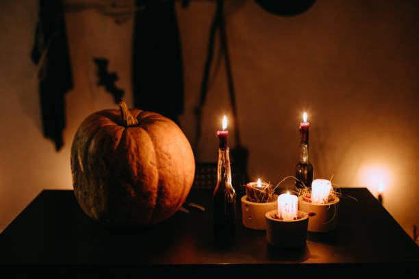 A big pumpkin is next to  candles in a dark room. Preparation for Halloween