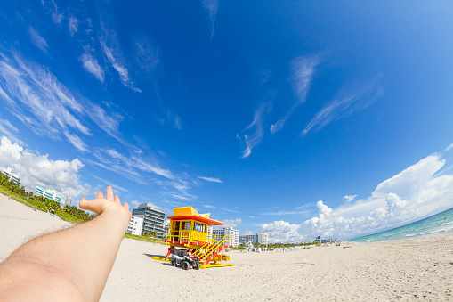POV Point of view shot of a young male having fun in South Beach, Miami Beach, Miami, South Florida, United States of America in front of a classic art deco lifeguard house.

Shooting from a personal perspective in an exotic tropical beach travel holidays.