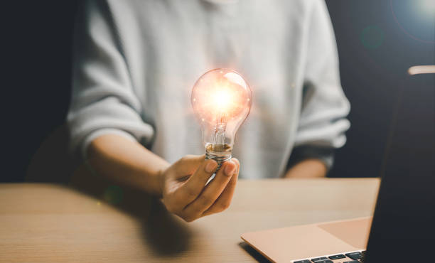 istock woman holding a light bulb Show inspiration, ideas, innovation and imagination, problem solving and technology, business creativity for a successful brainstorming session. notebook on table. 1426623891