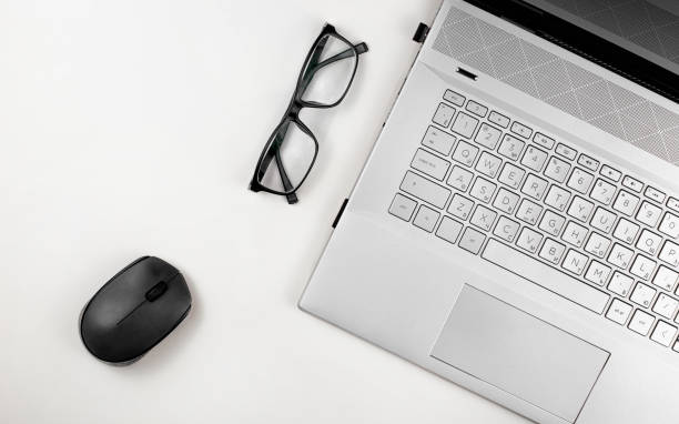 istock A laptop with glasses and computer mouse are on a white table. Top view with copy space 1426627706