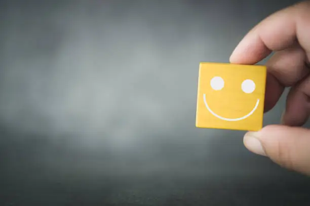 Photo of Hands holding happy smile face on wood block, good feedback rating.