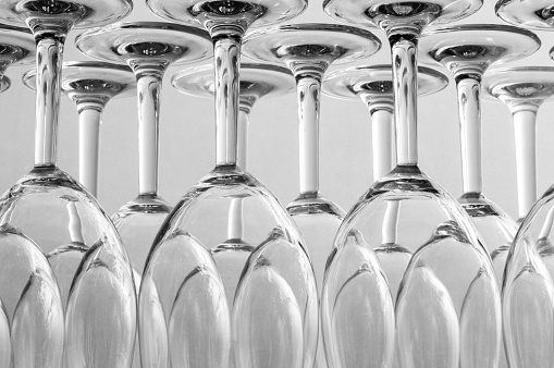 Close up of empty wine glasses stored upside down on a shelf.