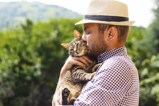 istock Man in hat gently kissing his cat. 1426632669