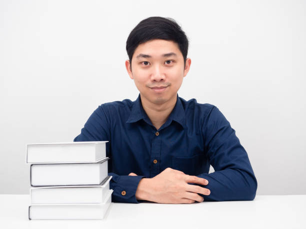 Asian man confident looking at camera with the books on the table