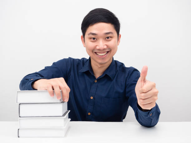 istock Cheeful man smile and thumb up with the books on table 1426633249