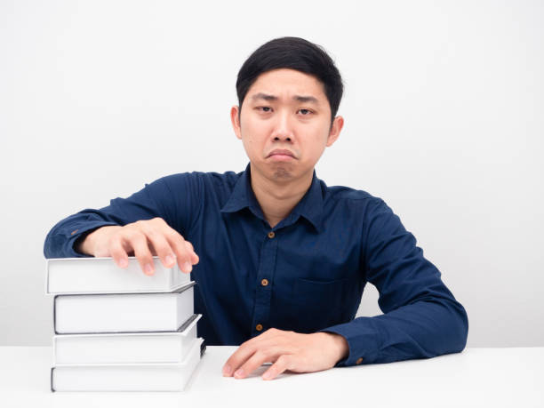 istock Asian man feeling bored about reading books on the table white background 1426633260