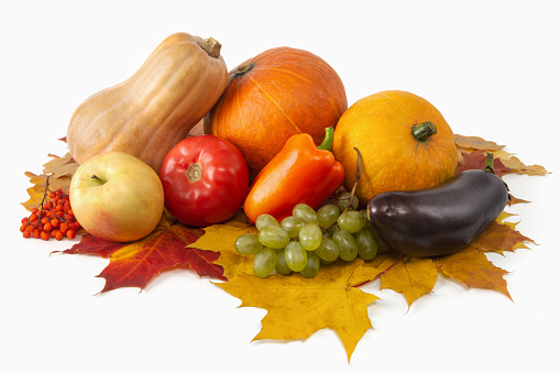 Heap of various vegetables and fruits with pumpkin and maple leaves on a white background. Harvest concept. Isolated.