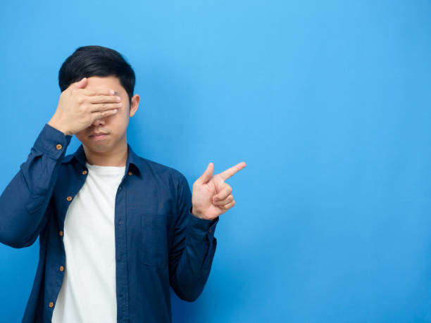istock Asian man close eyes point finger at copy space blue background 1426636902