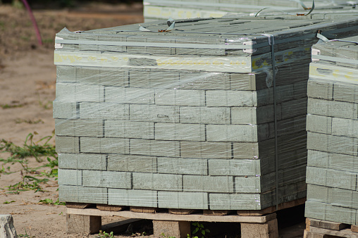 A pile of new bricks at construction site sitting on wooden flat. We have other construction images in our portfolio.