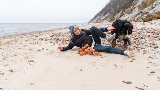 Woman with her Bernese Mountain dog playing on the beach of the Baltic sea in winter. Kaliningrad Region, Russia, Eastern Europe.