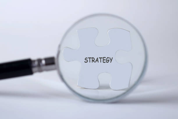 istock Strategy word with hand holding magnifying glass over jigsaw puzzle 1426649129