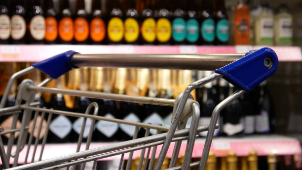 Close-up of a shopping carts handle and a blurred display case with beverages behind it stock photo